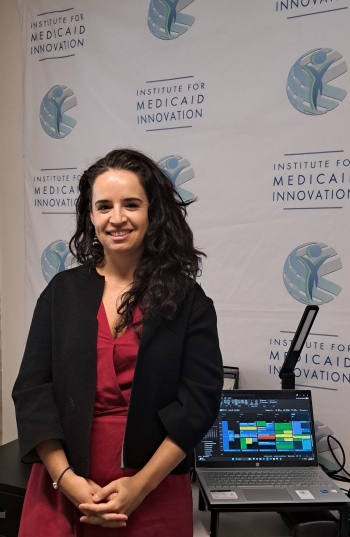 ASU PhD candidate Frida Espinosa Cárdenas smiiling in front of a wall with the words "Institute for Medicaid Innovation."