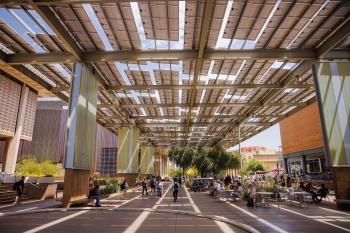 Students walk around campus underneath solar panels.
