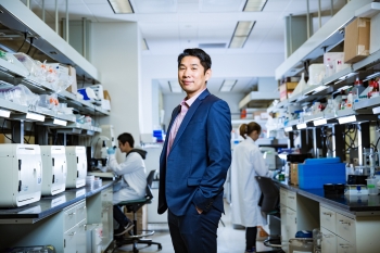 Hao Yan standing in a lab wearing a suit with his hands in his pockets.