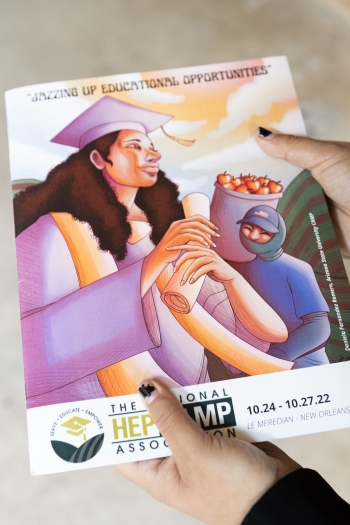 Daniela Fernández Romero's hands holding the The National HEPCAMP Association Annual Conference program featuring her artwork on the cover