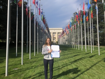 woman standing in front of United Nations flags with certificate