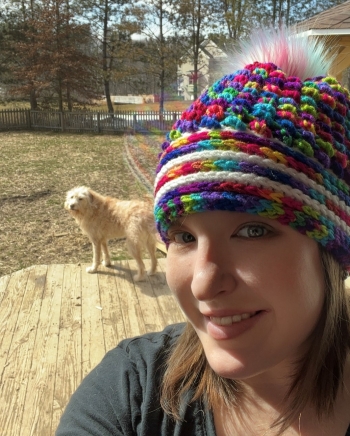 Anna Gutmann is photographer wearing a mutli-colored knitted hat next to her big golden-colored dog.