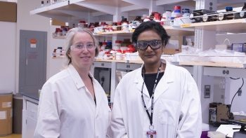 two women wearing white coats in a lab