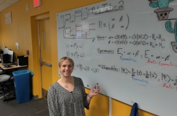 ASU College of Integrative Sciences and Arts applied physics graduate Addison Olsen smiles while standing in front of whiteboard.