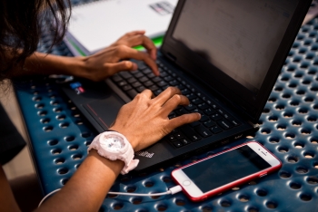 A high schooler's hands working on a laptop