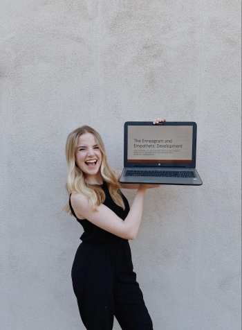 Claire holding up a laptop on a screen related to her field of study