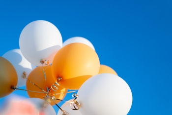 Gold and white balloons against a blue sky.