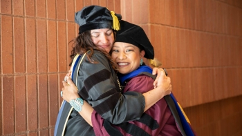 professor and student embrace at doctoral degree graduation ceremony