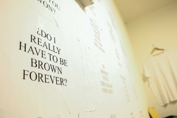 Words on a wall as part of an art exhibit that read "Do I really have to be brown forever?"