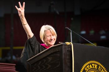 A woman flashes the ASU pitchfork gesture at a commencement speech