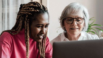 Younger woman and older woman working together on a laptop.