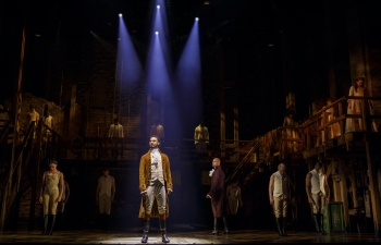 The cast of the Broadway musical Hamilton stands onstage.