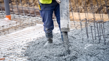 Construction worker pouring concrete into a building foundation.