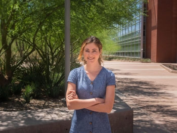 fourth-year clinical psychology graduate student Sarah Curci stands smiling, with arms folded, in front of a tree on ASU's Tempe campus