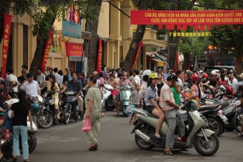 Night shot of pedestrians crossing road full of mopeds in busy