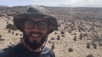ASU graduating PhD Donald Glaser posing for a selfie in a desert landscape.