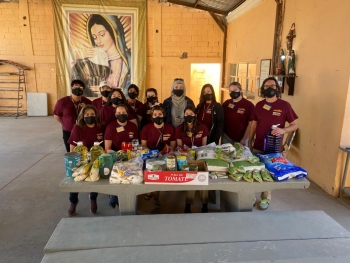 ASU social work students pose for a group photo behind a table full of donated food at Casa de Migrantes in Hermosillo, Sonora, in Mexico.