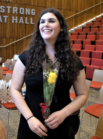 ASU BSN graduate Elliana Tenenbaum smiling and holding a yellow rose in an auditorium.