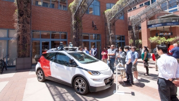 A crowd observes an electric autonomous vehicle.