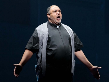 man dressed as a reverend, singing on stage