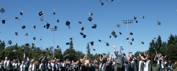 People throwing their graduation caps into the air at a high school graduation ceremony.
