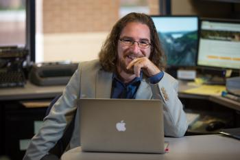 ASU professor Greg Wise sits at a laptop in his office