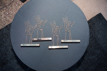 Awards fashioned out of gold wire in the shape of the ASU pitchfork against a black backdrop.