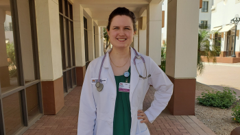 Hannah Challa wears her white nurse practitioner coat with a stethoscope around her neck. 