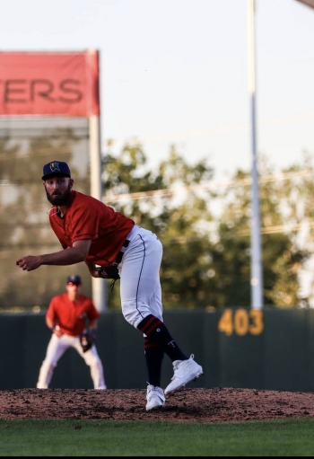 Professional baseball player Zach Featherstone pitches the ball at a Minor League game.