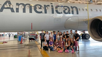 Group of ASU students pose in front of American Airlines plane.
