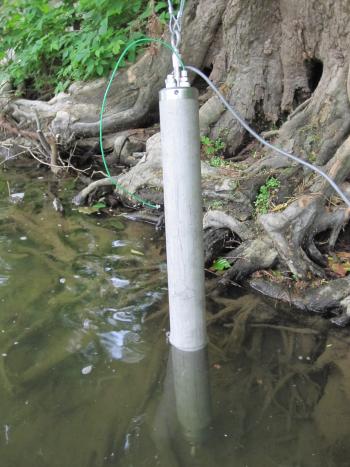 An in situ water contaminate sampling device in use, looks like a metal tube in a river.