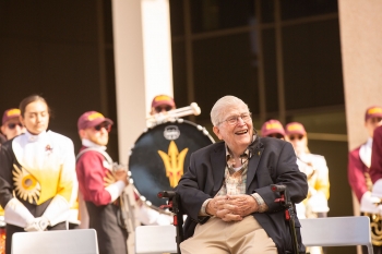man smiling and sitting in front of marching band at event