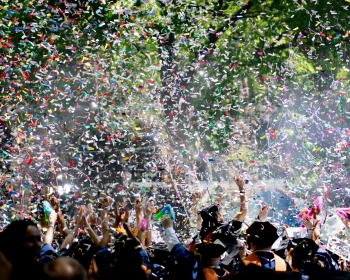 College graduates celebrate as confetti swirls.