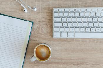photo of keyboard with coffee mug and notebook