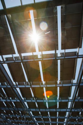 solar panel structures over parking lot with sun peeking through