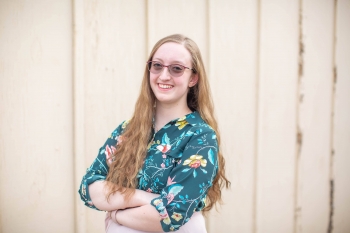 Madeleine Steppel photographed in a multi-colored button down shirt, wearing dark glasses.