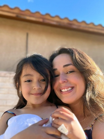 Magan Martinez holds her daughter, smiling and looking at the camera.