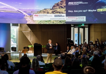 ASU President Michael M. Crow speaks at the Arizona Water Innovation Initiative launch, standing in front of a group of people with a microphone.