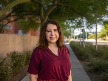 Portrait of Megan Nelson, an undergraduate student in the ASU Department of Psychology. Nelson stands on a sidewalk under a tree. She has shoulder-length brown hair and wears a burgandy blouse while smiling at the camera.