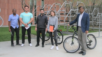 Professor Ram Pendyala's transportation research team and himself posing near a bike rack on campus.