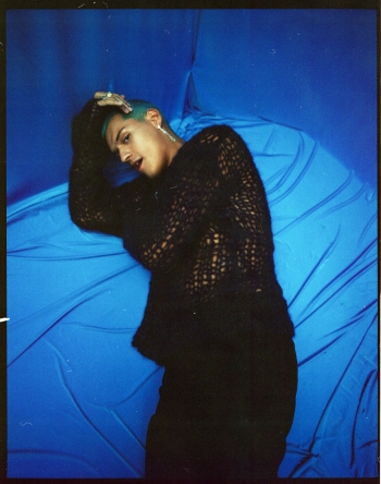 Omar Apollo laying on blue silk floor