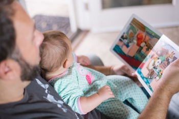 A father reads out loud to his baby.