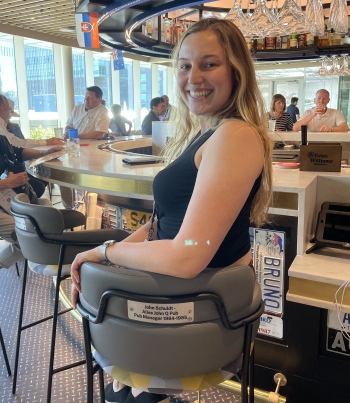 Julie Schuldt sitting on a stool at a round bar, looking over her shoulder and smiling.