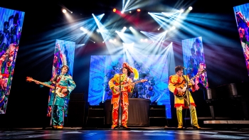 Members of Rain: A Tribute to the Beatles perform on stage.