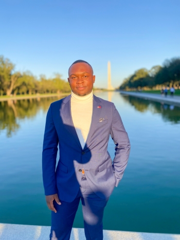 ASU student Simon Anthony Lee wearing a blue suit, standing in front of the Lincoln Memorial reflecting pool in Washington, D.C.