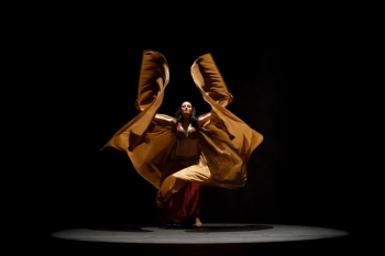 belly dancer is shown in an dramatic pose in a gold winged costume