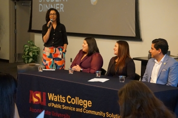 Panelists sit or stand at a Watts College table.