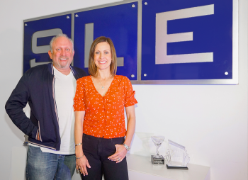 Steve LeVine and Jamie Morris LeVine in front of an SLE sign