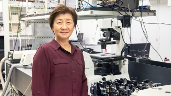 Su Lin standing in a lab, looking at the camera.