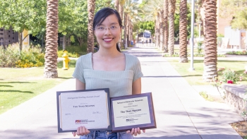 Thu Thao Nguyen, recipient of the 2022 Innovation Award from ASU's School of Molecular Sciences, smiling and holding two plaques on palm walk on the Tempe campus.